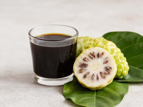 Noni Saft im Glas mit Früchten